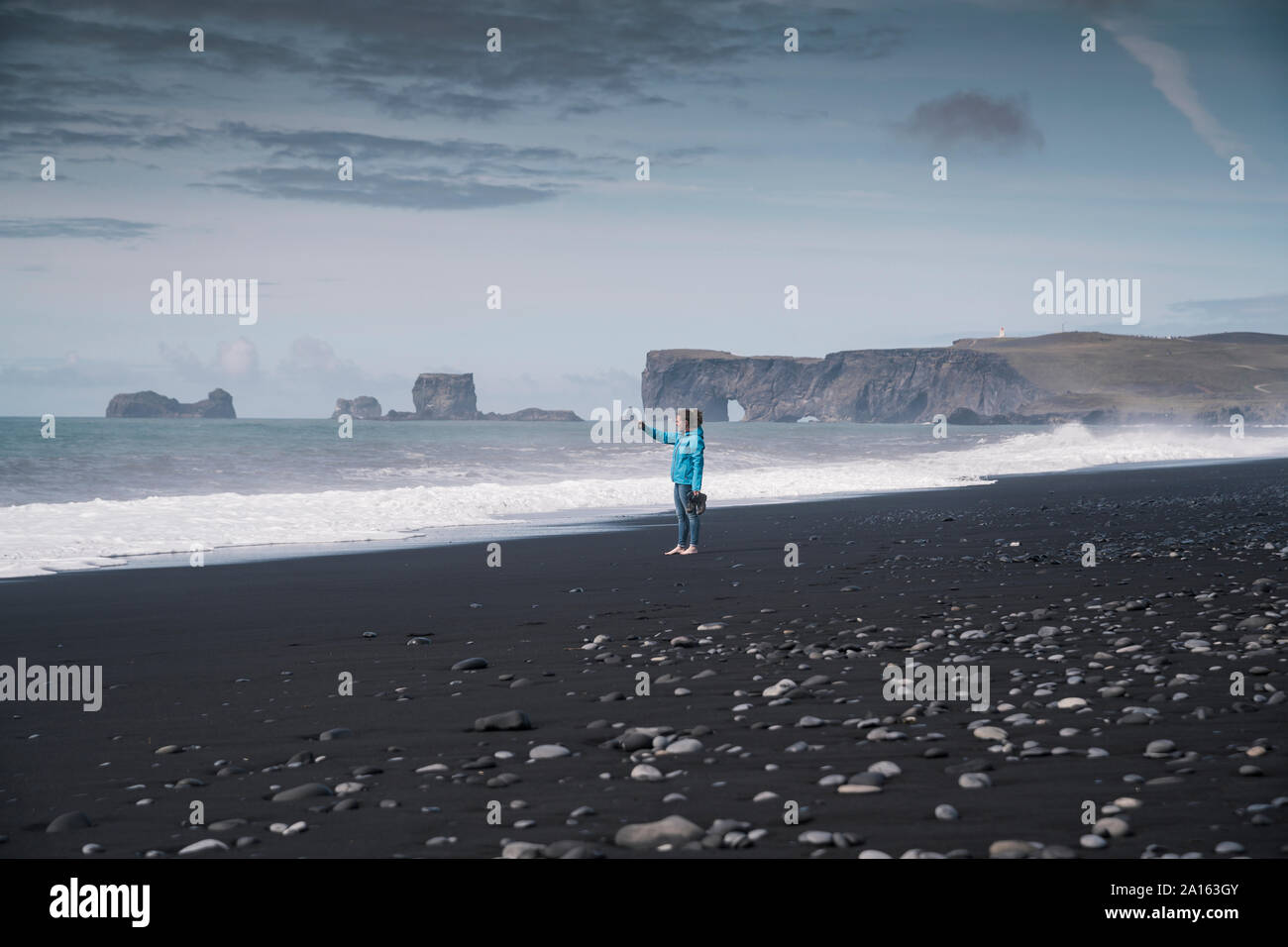 Jeune femme prendre des photos sur une plage de lave en Islande Banque D'Images