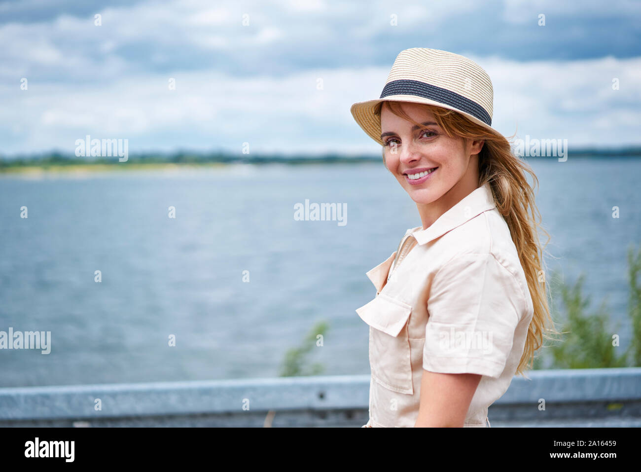Portrait of smiling woman with hat au bord de lac Banque D'Images