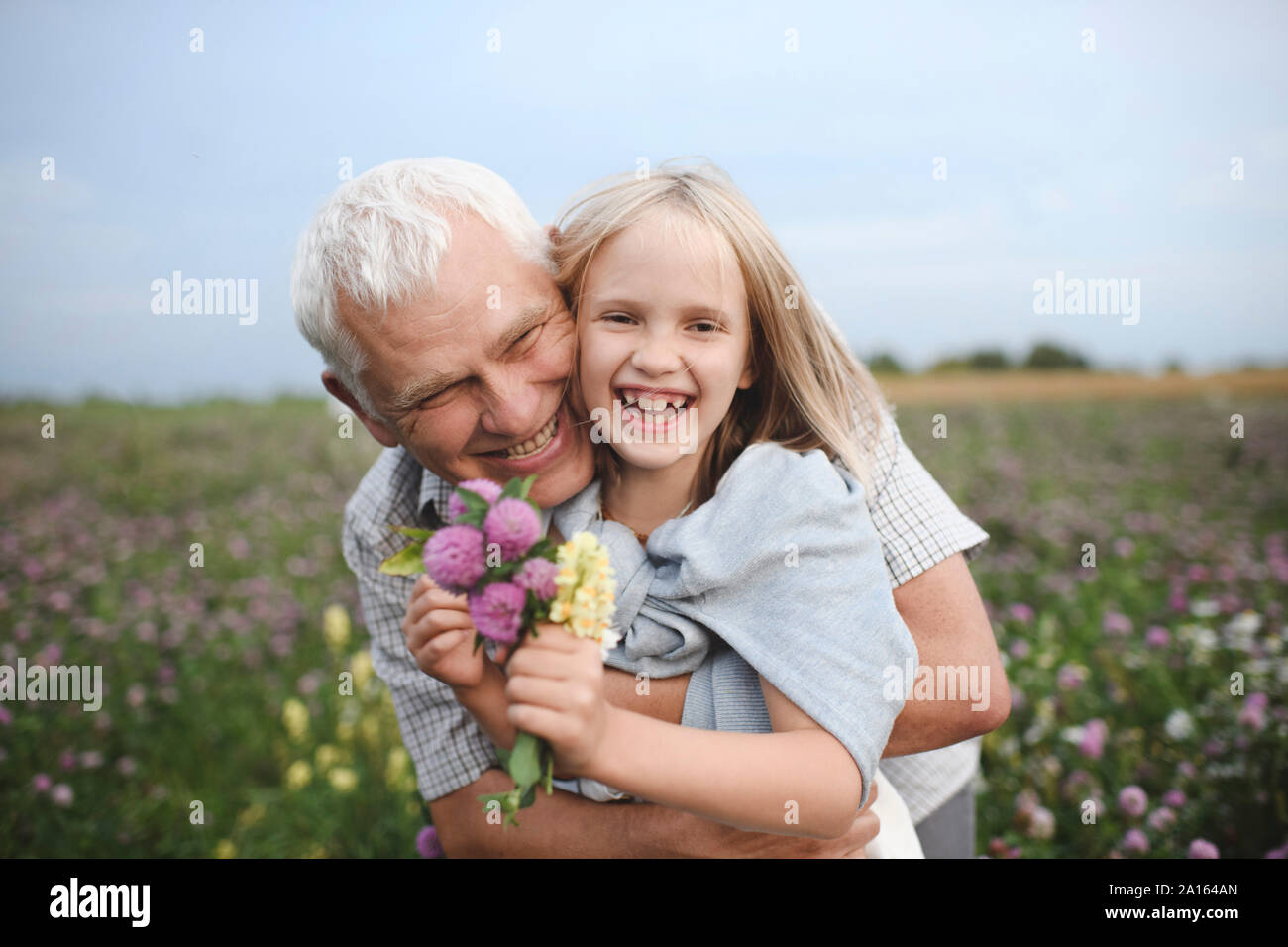 Portrait de rire grand-père et sa petite-fille avec des fleurs cueillies sur un pré Banque D'Images