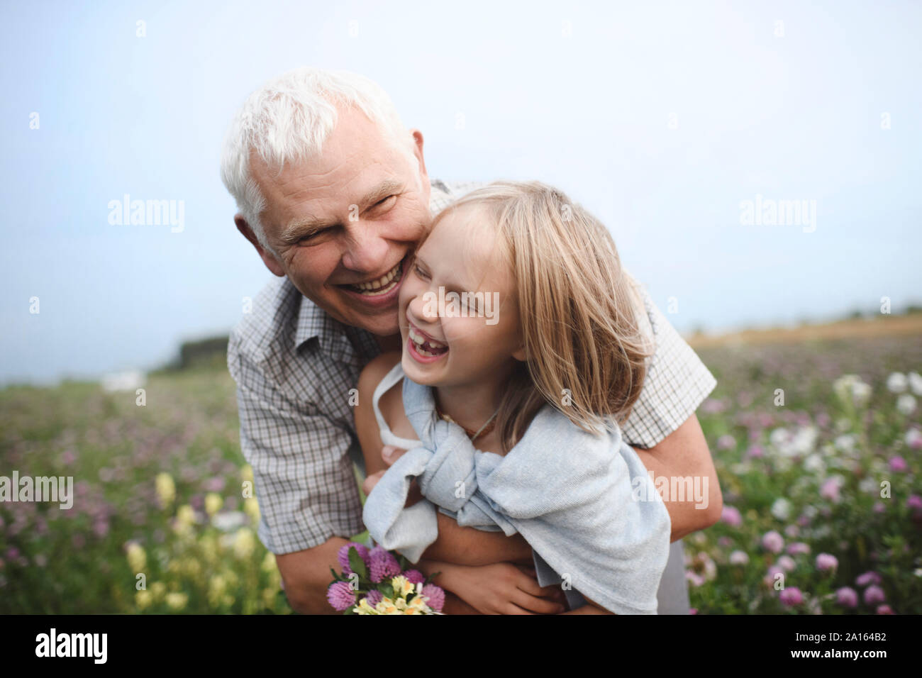 Rire grand-père et sa petite-fille avec des fleurs cueillies sur un pré Banque D'Images