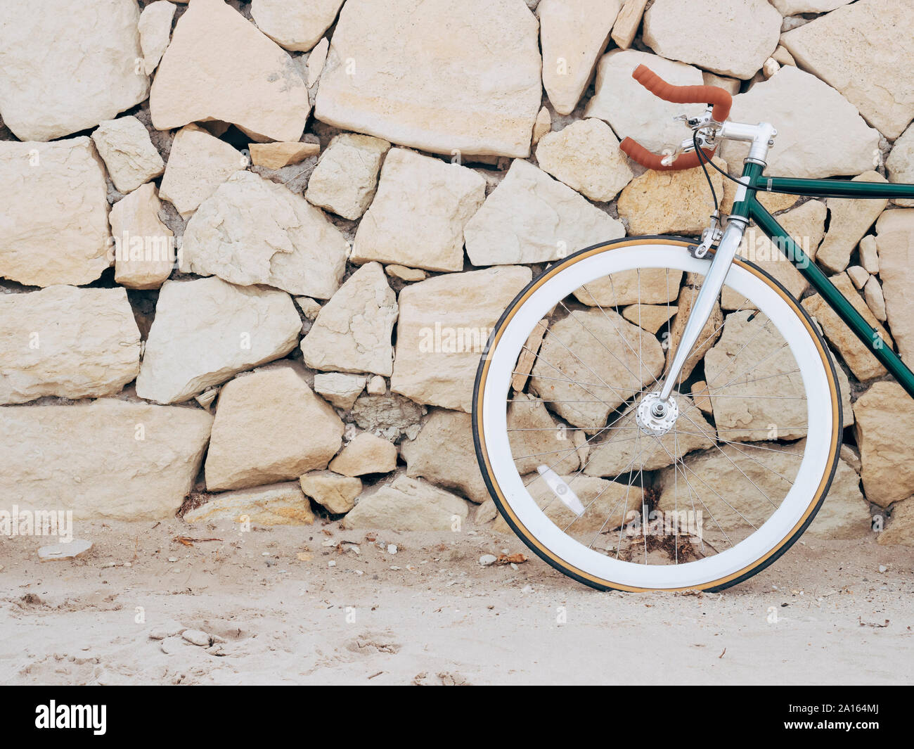 Vélo Fixie appuyé contre mur en pierres naturelles, vue partielle Banque D'Images