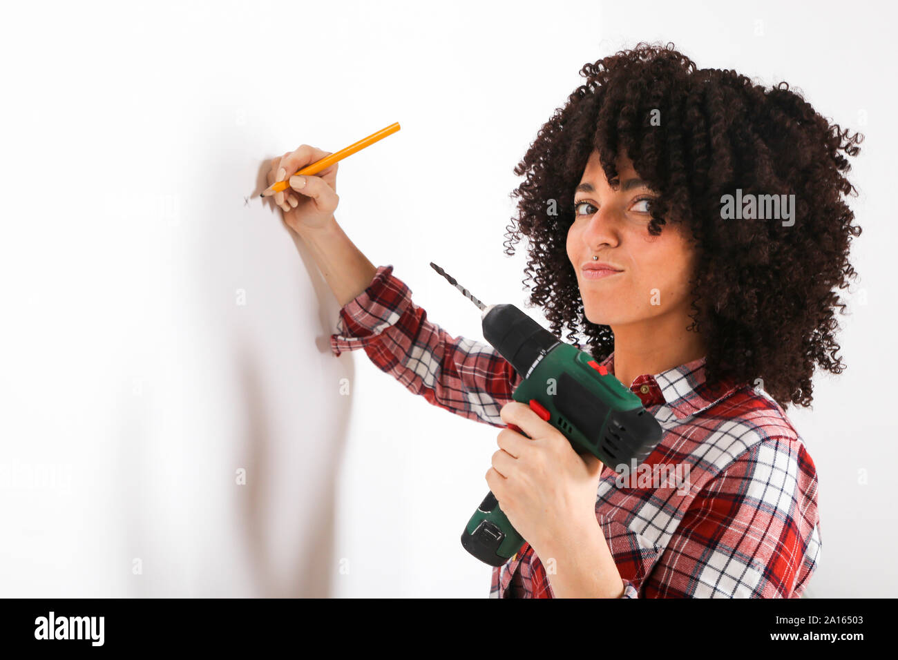 Femme à l'aide de support de forage, marquage au crayon sur un mur Banque D'Images