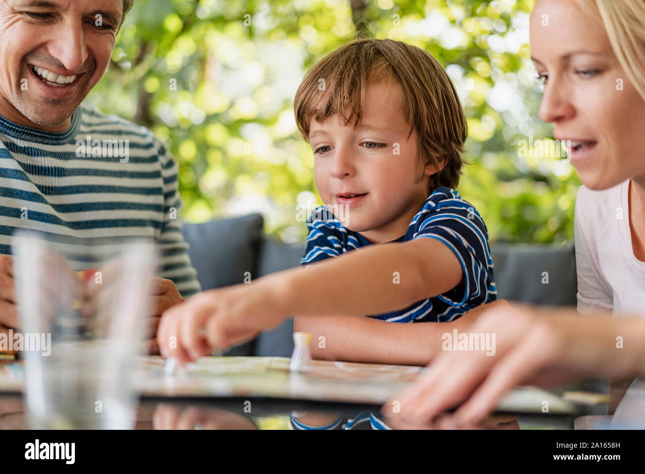 Heureux parents et son fils jouer à un jeu de société sur la terrasse Banque D'Images Heureux parents et son fils jouer à un jeu de société sur la terrasse Banque D'Images