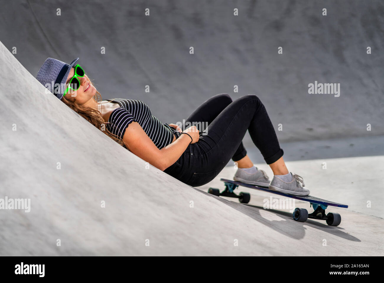 Jeune femme avec skateboard couché dans skatepark Banque D'Images