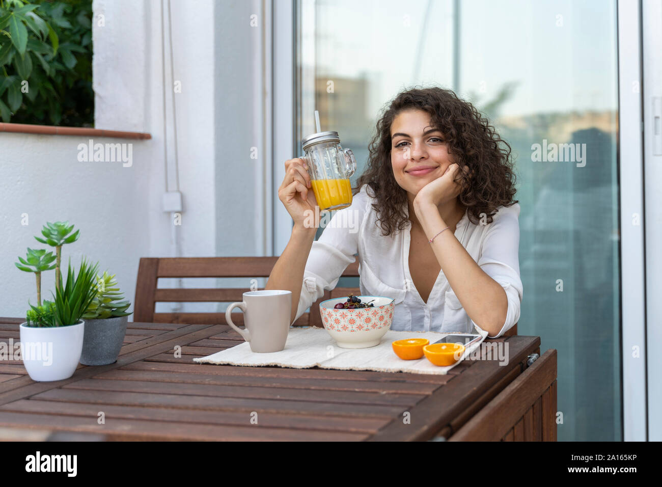 Portrait de jeune femme avec du jus d'orange sur balcon Banque D'Images