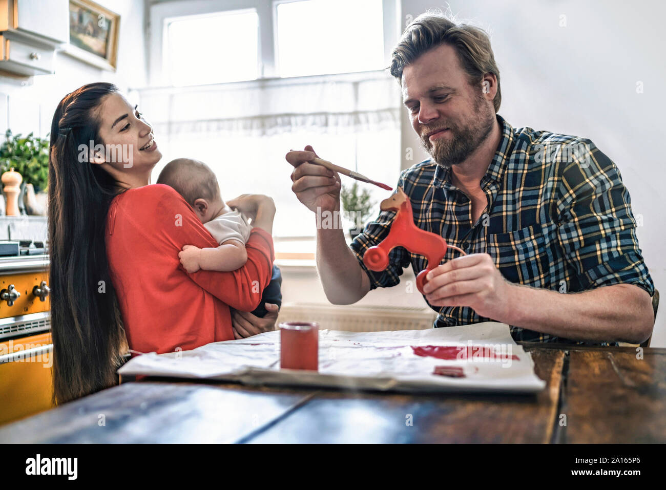 La peinture de la famille cheval jouet en bois pour bébé à la table de cuisine à la maison Banque D'Images