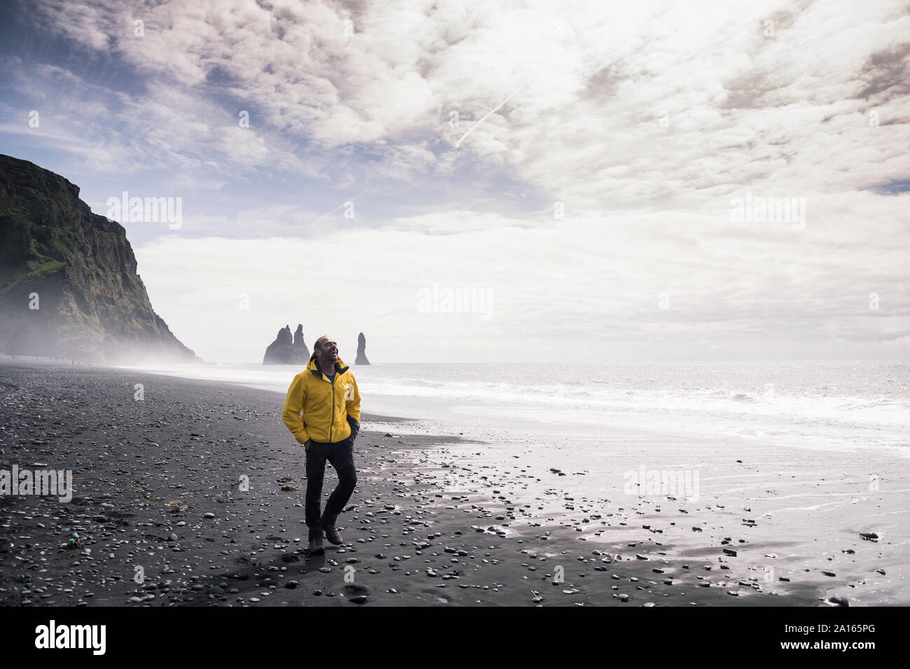 Man marche sur une plage de lave en Islande Banque D'Images