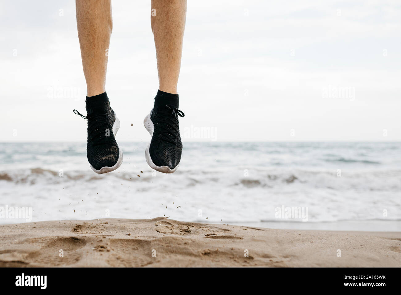 Les jambes de l'homme sautant sur la plage alors que la formation Banque D'Images