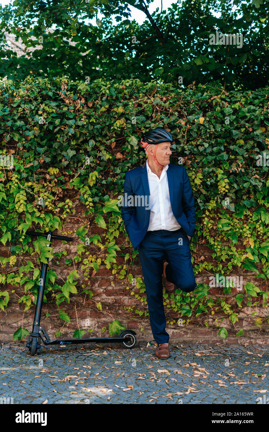 Man avec l'e-scooter appuyé contre un mur Banque D'Images