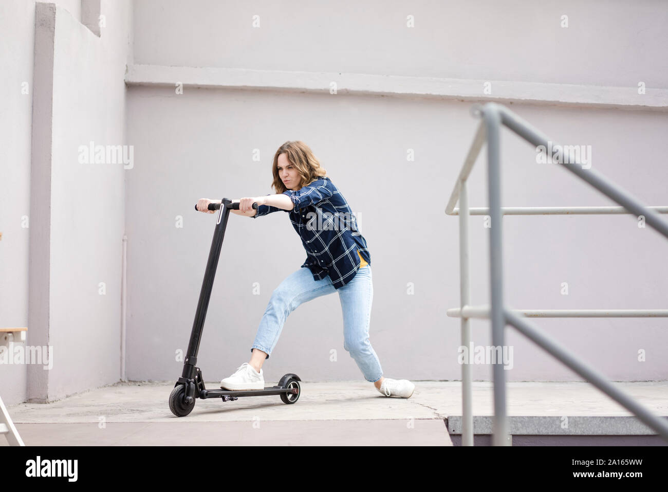 Jeune femme avec scooter électrique en un loft Banque D'Images