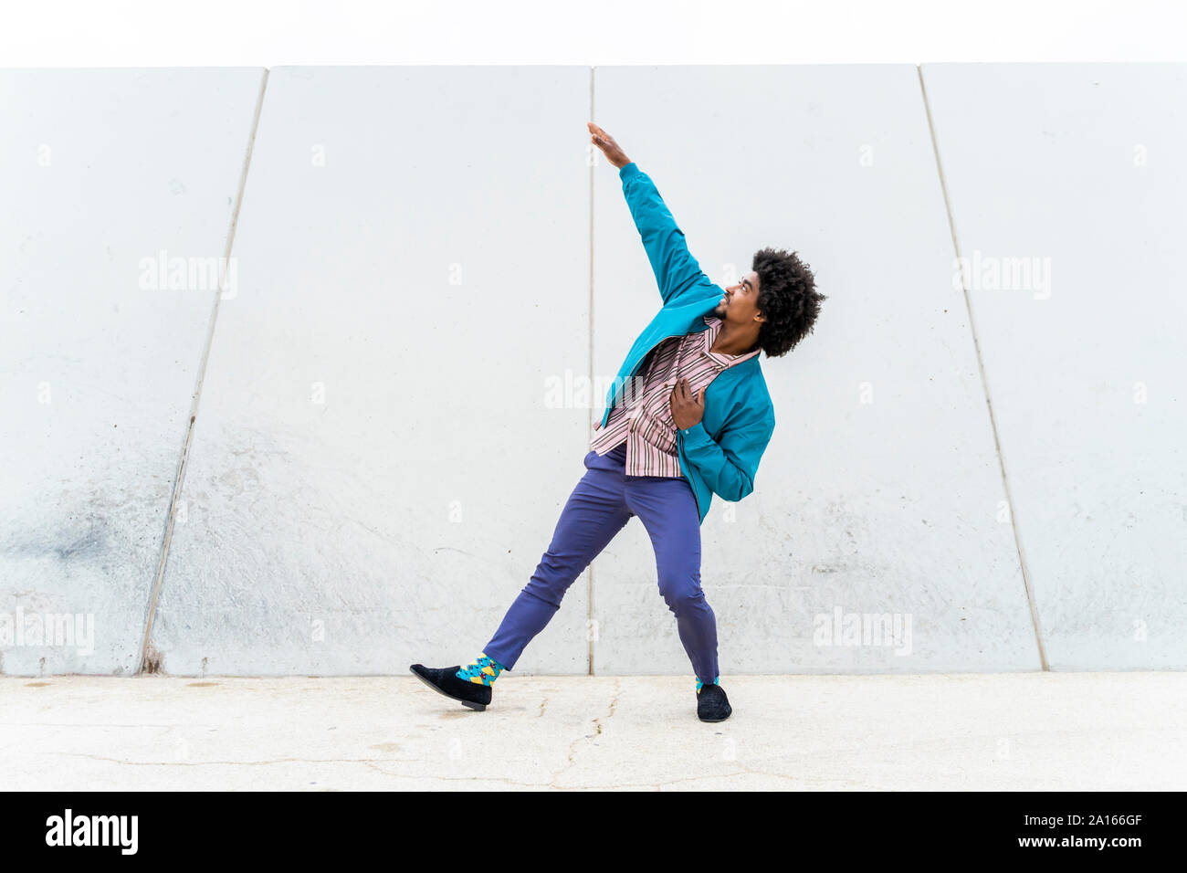 Jeune homme hipster danse, mur blanc en arrière-plan Banque D'Images