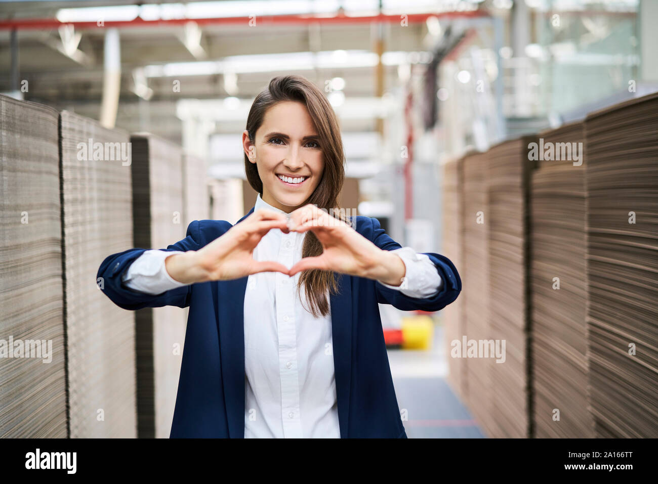 Portrait of happy businesswoman en usine-entrepôt façonner un coeur avec ses mains Banque D'Images