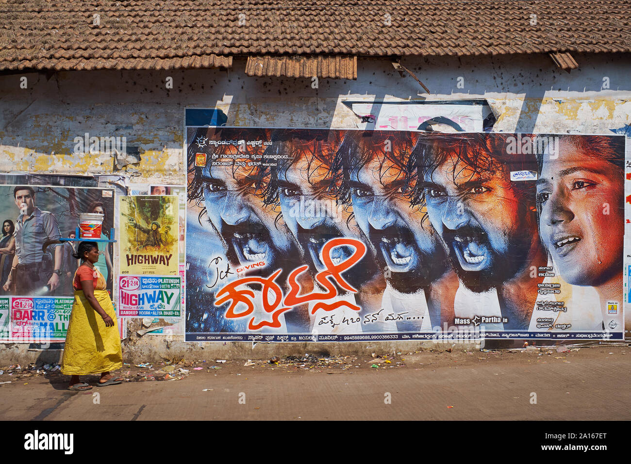 Une femme à Mangalore, Karnataka, Inde, l'équilibrage des seaux de peinture vides sur la tête, passe une grande peur, une affiche publicitaire de langue Kannada film Banque D'Images