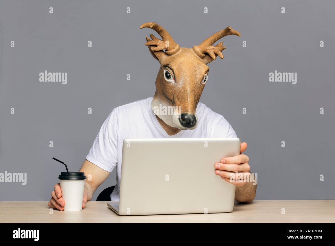L'homme avec masque à l'aide de cerfs, ordinateur portable pour aller boire du café tasse Banque D'Images