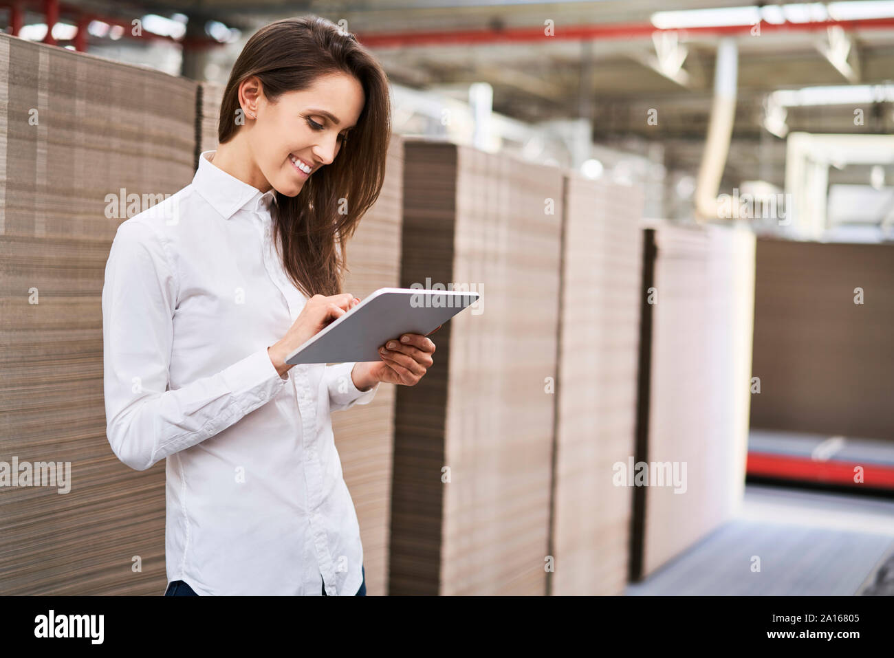 Smiling young woman using tablet dans une usine-entrepôt Banque D'Images