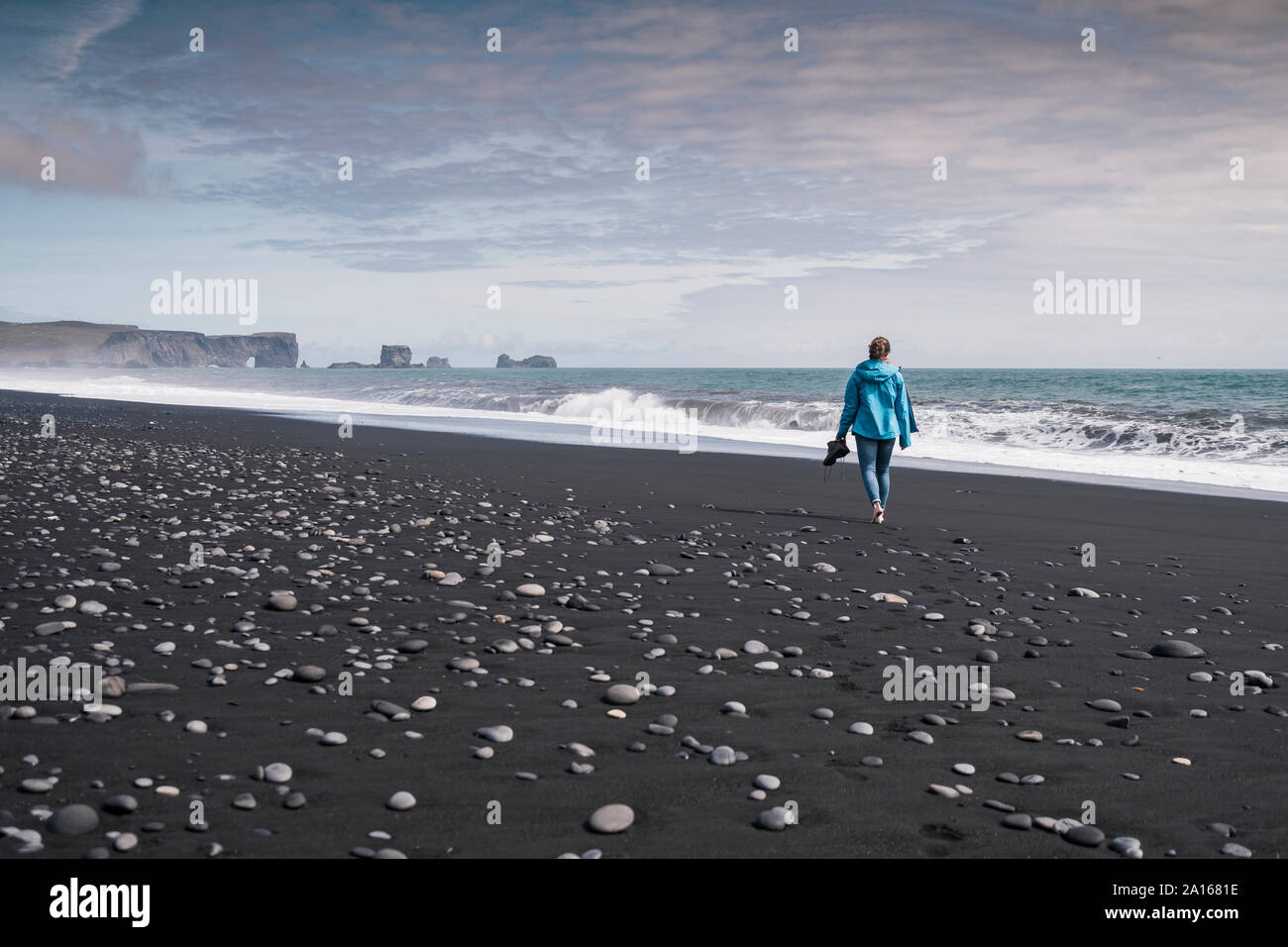 Jeune femme marche sur pieds nus sur une plage de lave en Islande Banque D'Images