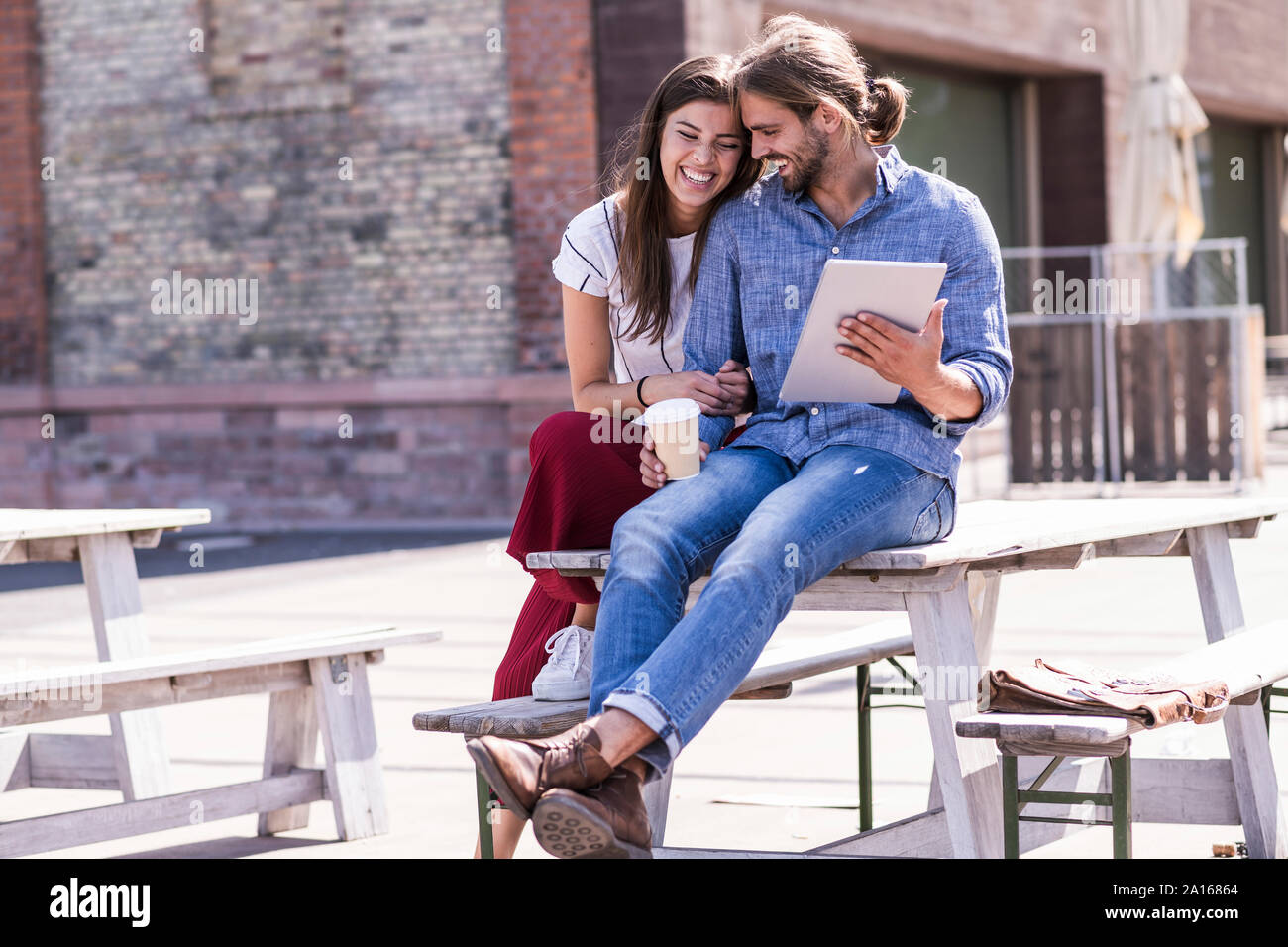 Happy young couple sitting on table dans un café en plein air avec tablet Banque D'Images