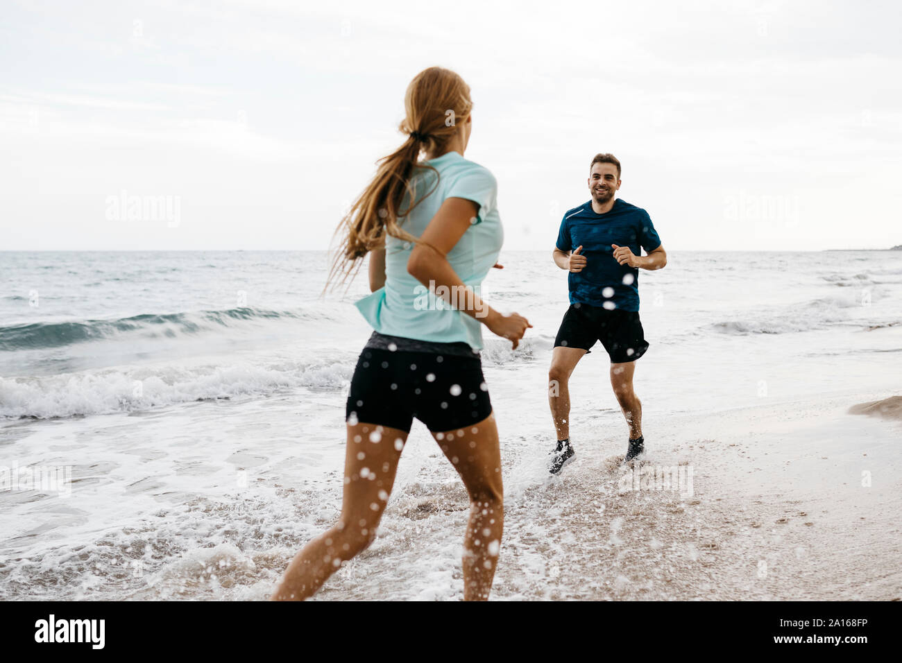 Jeune couple jogging sur la plage Banque D'Images