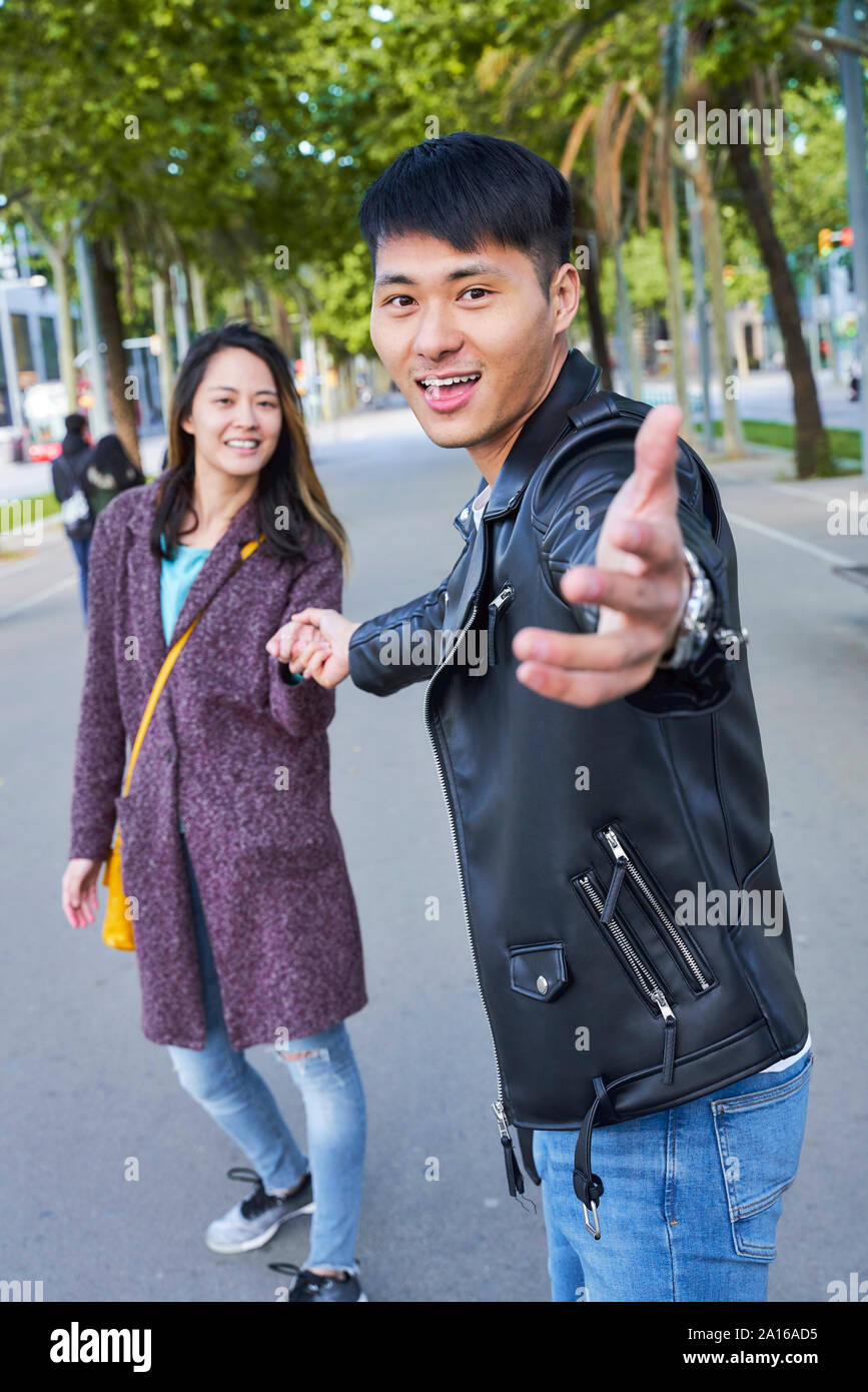 Heureux couple inviter quelqu'un à se joindre à eux pour une promenade, Barcelone, Espagne Banque D'Images