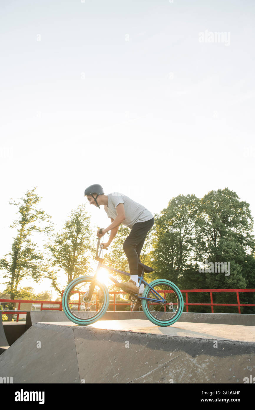 Jeune homme équitation vélo BMX au skatepark au coucher du soleil Banque D'Images