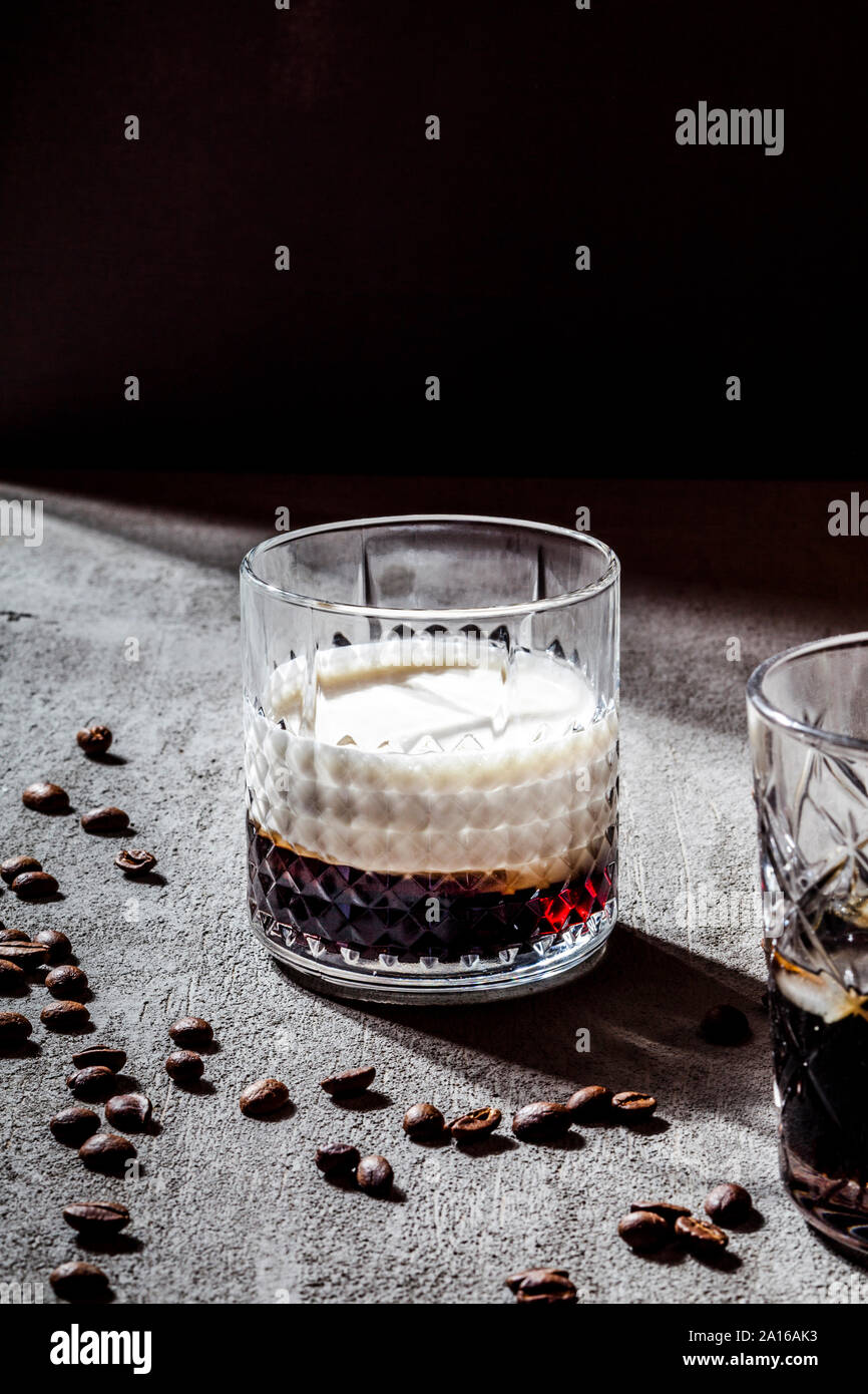 Close-up of White Russian dans du verre par les grains de café torréfiés sur table béton Banque D'Images