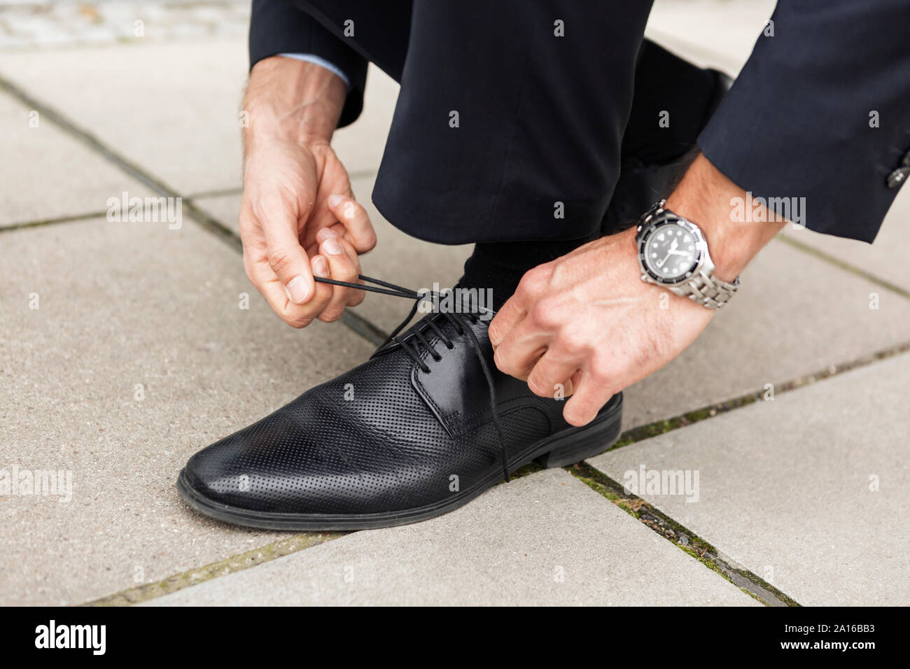 Businessman tying sa chaussure sur la chaussée, close-up Banque D'Images