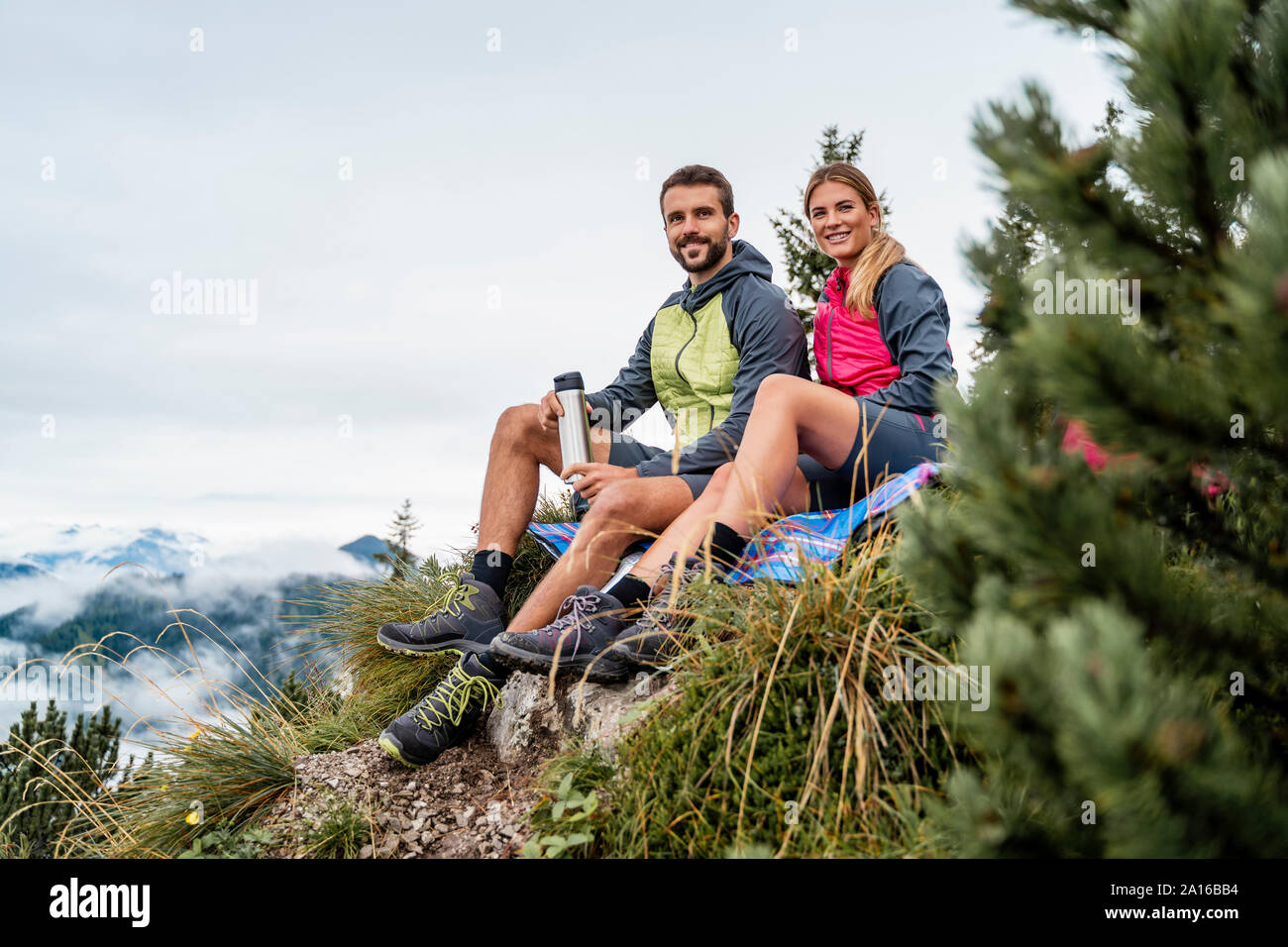 Jeune couple en randonnée dans les montagnes d'avoir une pause, Italia, Bavière, Allemagne Banque D'Images