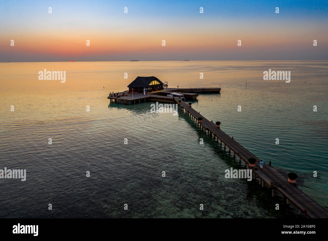 Les Maldives, l'île Olhuveli, Pier et immeuble sur South Male Atoll au coucher du soleil Banque D'Images