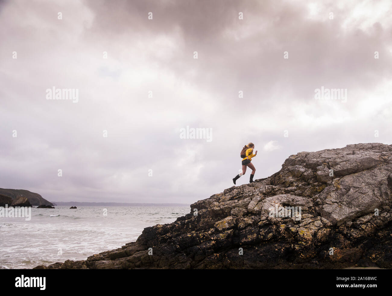 Woman Veste pluie jaune marche à la plage Banque D'Images