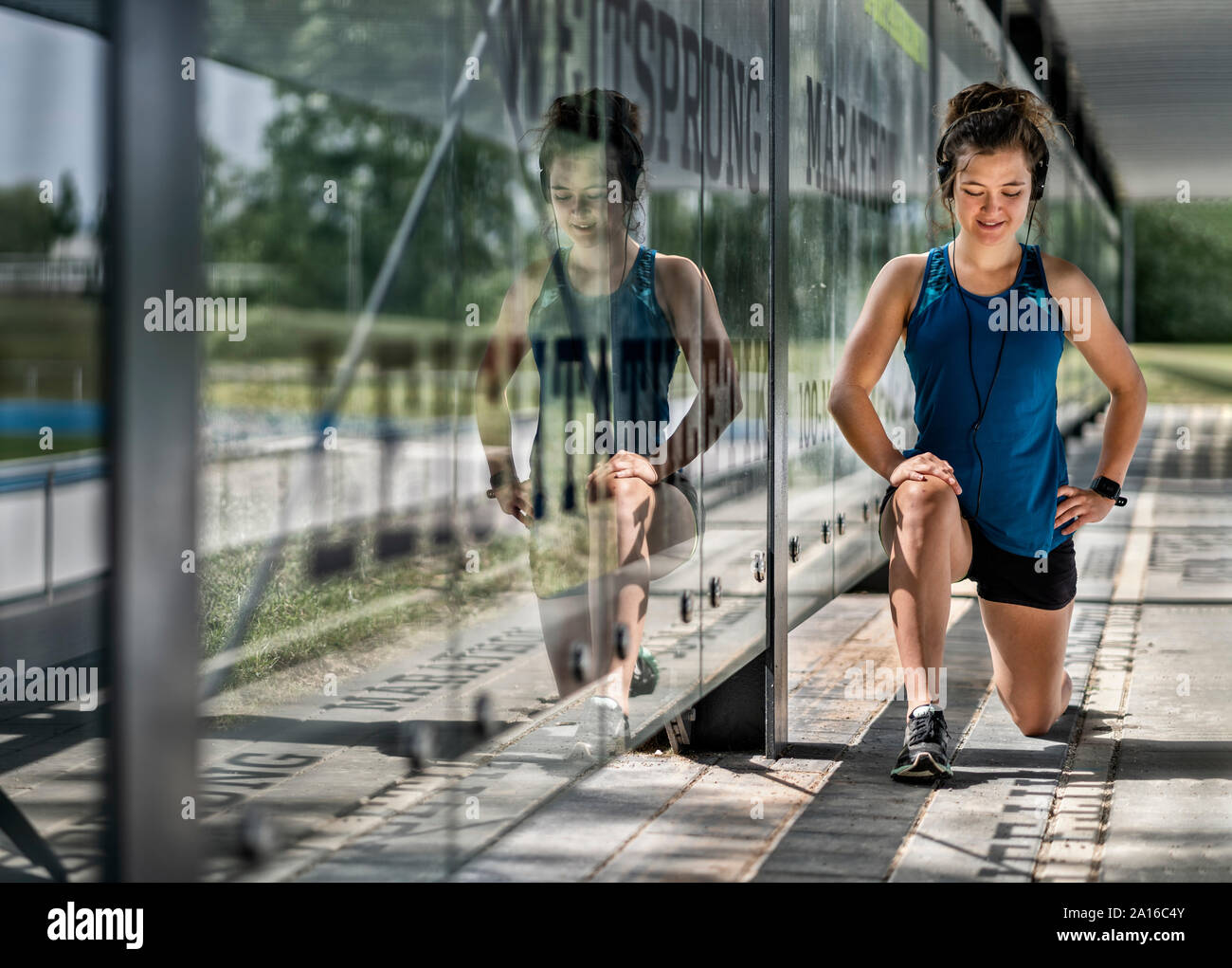 Jeune femme sportive portant des écouteurs et de faire l'exercice d'étirement Banque D'Images