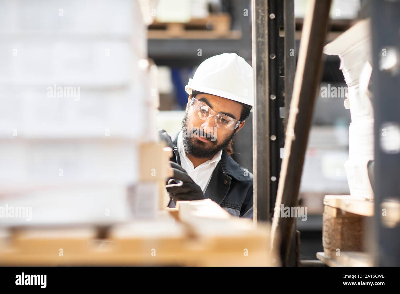 Young man wearing hard hat travaillant dans un entrepôt Banque D'Images