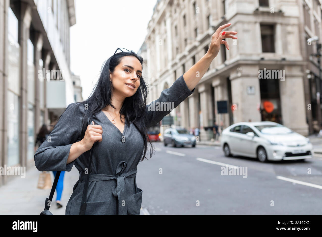 Femme dans la ville saluant un taxi, London, UK Banque D'Images