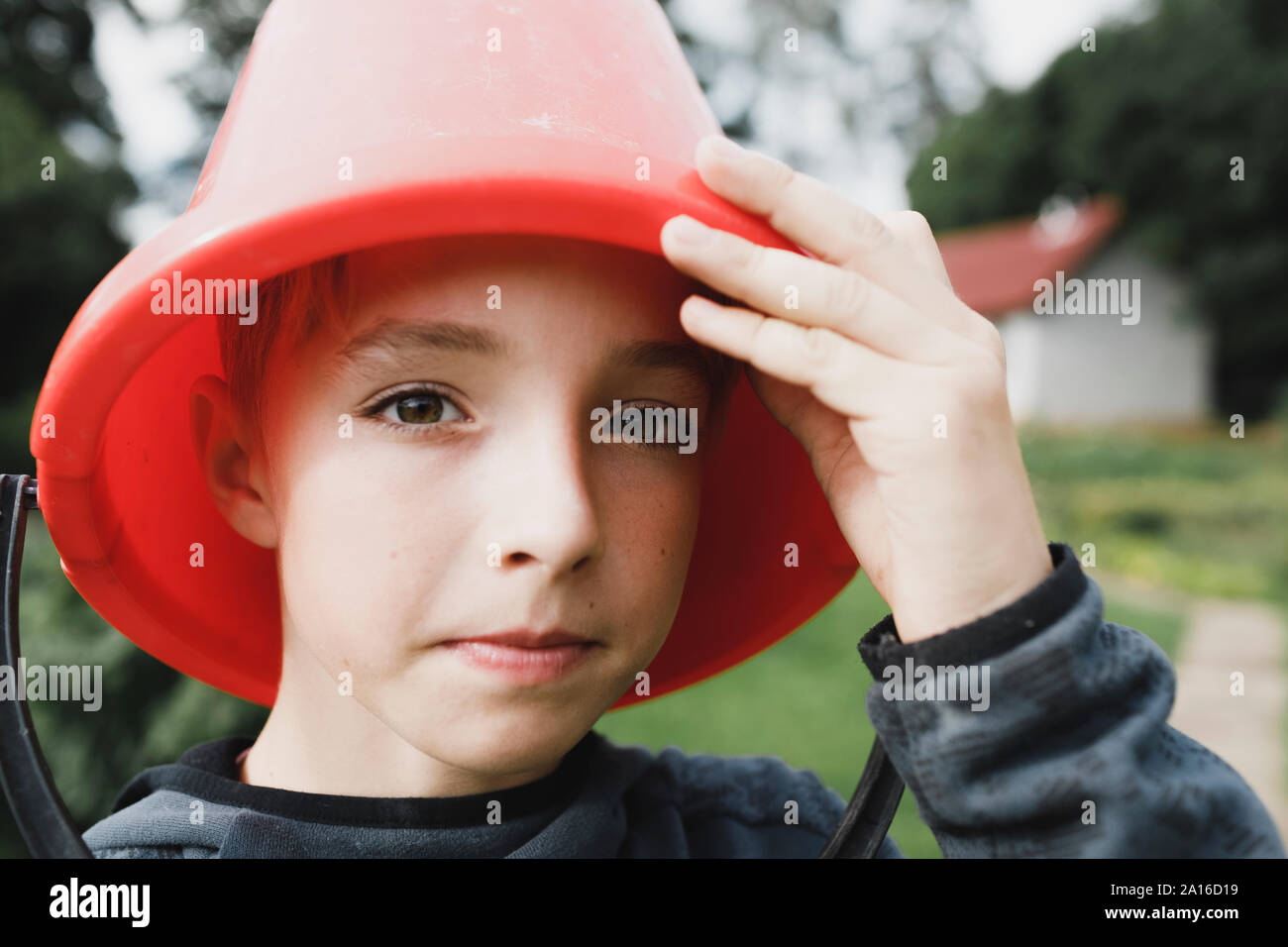 Portrait d'un garçon avec un seau rouge sur sa tête Banque D'Images