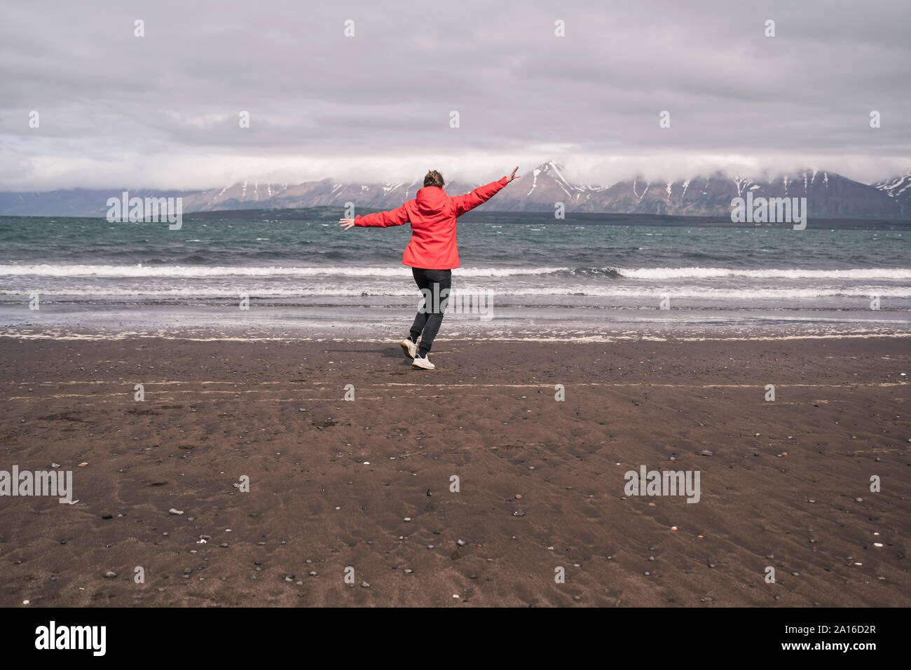 Jeune femme dansant sur une plage au fjord Eyjafjordur, Islande Banque D'Images