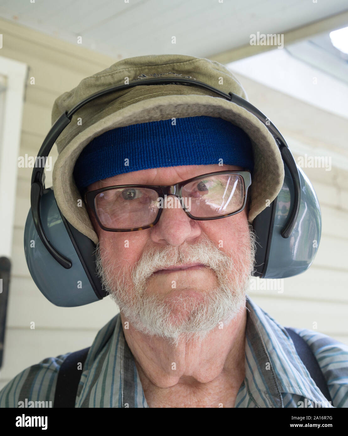 Vieil homme prêt à tondre avec son casque antibruit sur. Banque D'Images