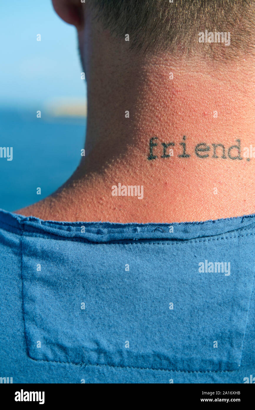 Gros plan d'une nuque d'un jeune homme avec mot ami tatoué Banque D'Images