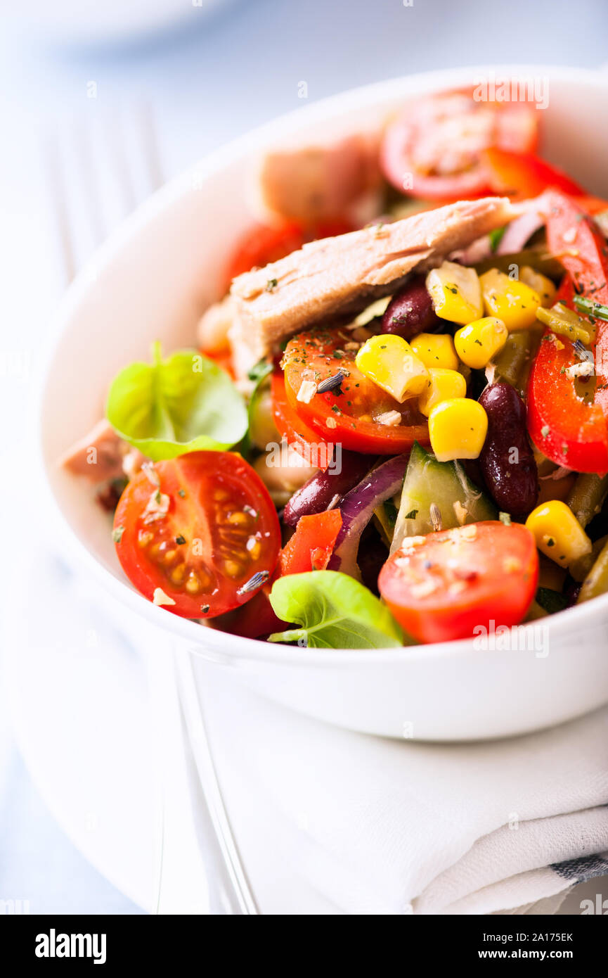 Salade de légumes mélangés avec du thon, haricots blancs et kindey, poivron rouge, maïs sucré, oignons rouges, persil et basilic frais. Banque D'Images