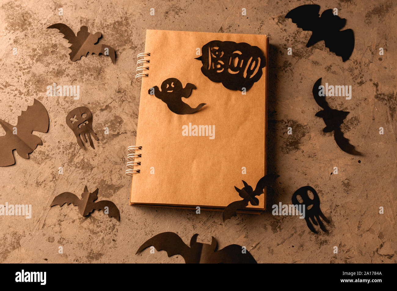 Les chiffres d'un black bat et fantômes taillée dans le papier noir sur une surface en béton. Le bloc-notes avec des feuilles d'artisanat et de copier l'espace. De l'artisanat pour l'halloween cele Banque D'Images