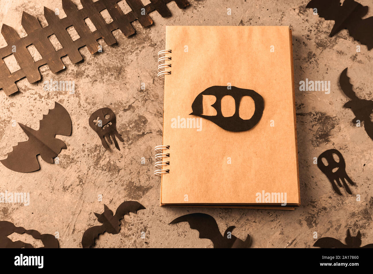 Les chiffres d'un black bat et fantômes taillée dans le papier noir sur une surface en béton. Le bloc-notes avec des feuilles d'artisanat et de copier l'espace. De l'artisanat pour l'halloween cele Banque D'Images