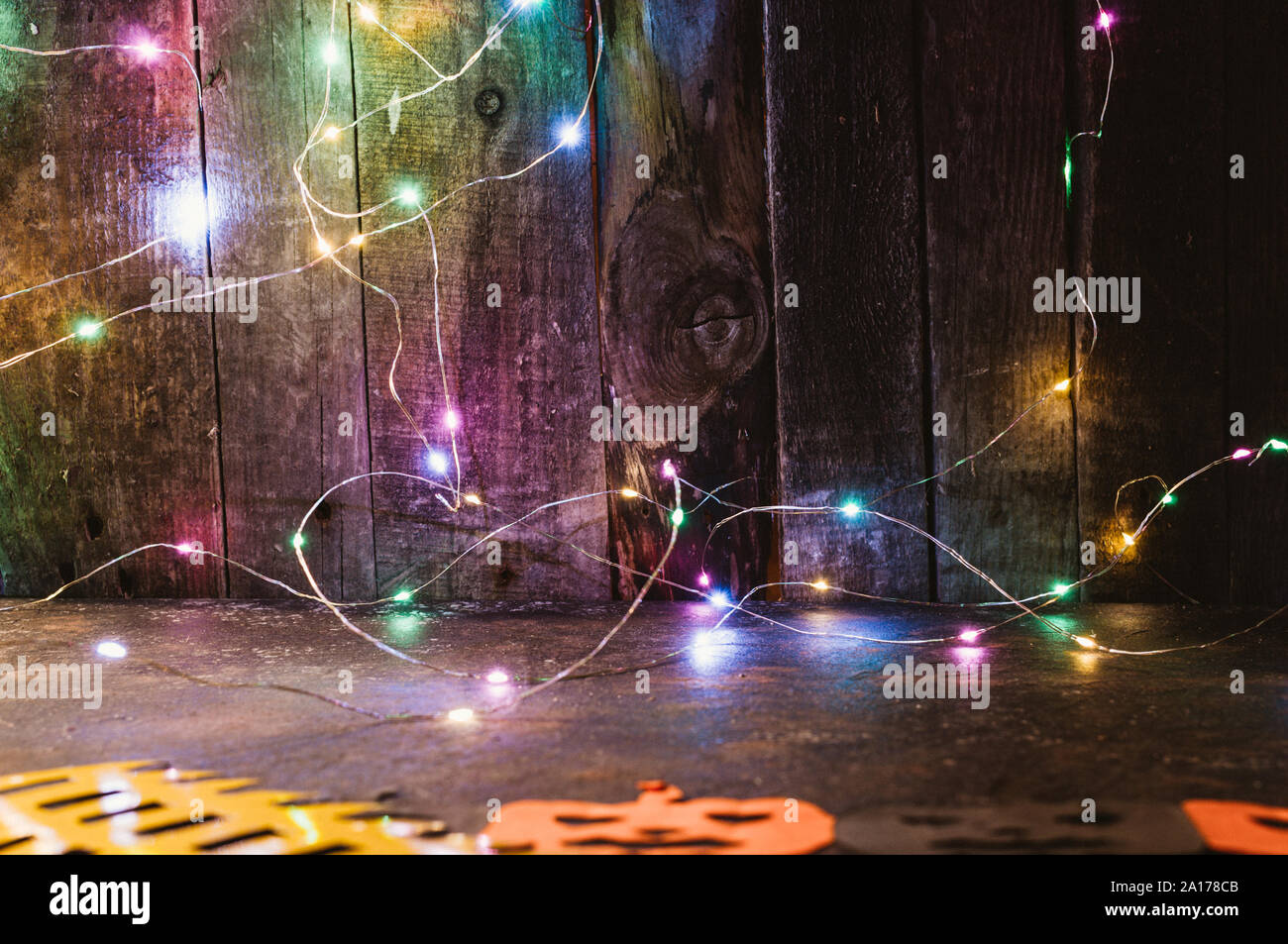 Guirlande LED de couleur sur un mur en bois sculpté et des citrouilles de l'orange sur la table. copier l'espace. De l'artisanat pour l'halloween concept. De couture. Banque D'Images