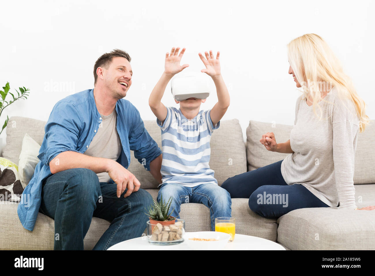 Famille heureuse à la maison sur salon canapé ayant l'amusement jouer des jeux à l'aide de casque de réalité virtuelle Banque D'Images