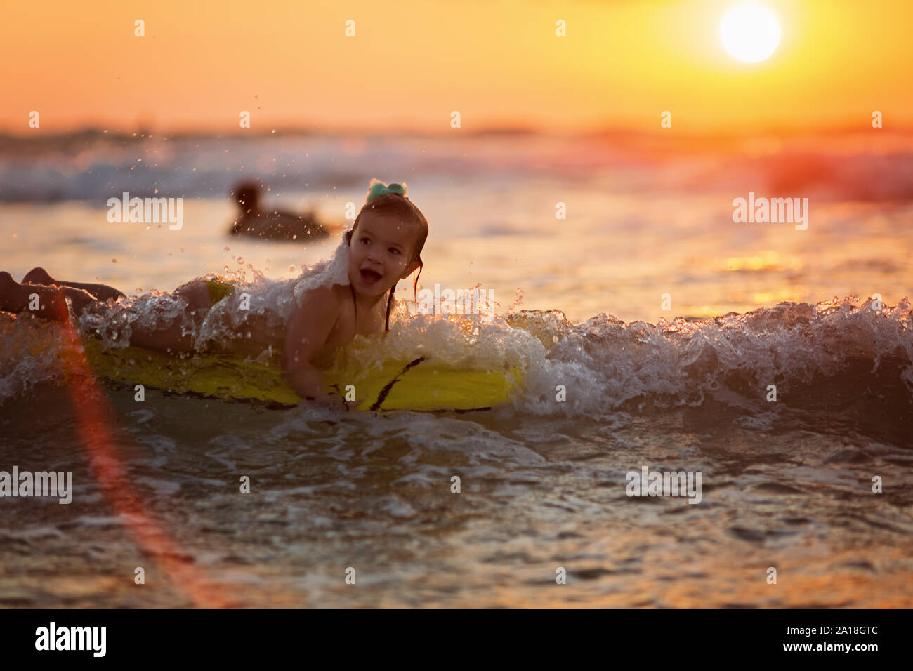 Petite fille conquiert de fortes vagues pendant la golden sunset Banque D'Images