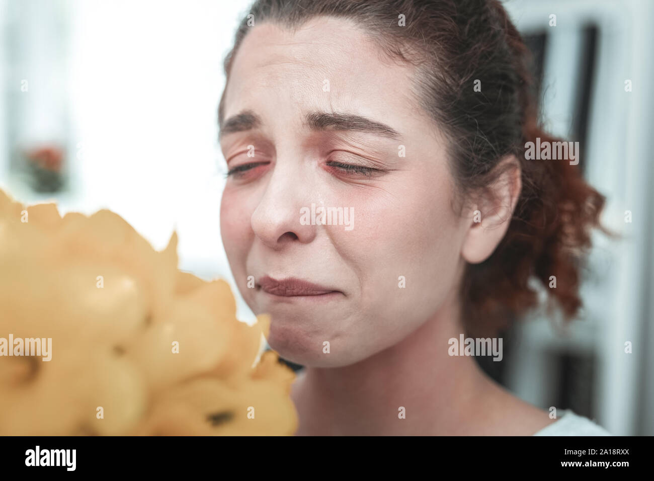 Femme au foyer bouclés ayant des larmes parce que de l'allergie aux fleurs Banque D'Images