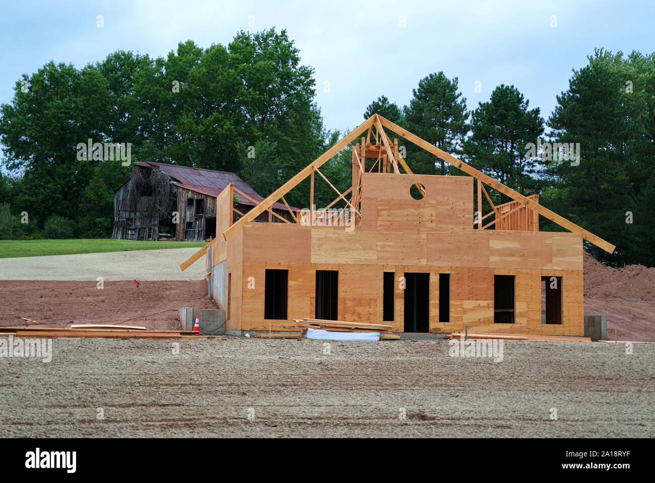 Une nouvelle maison ou à l'établissement d'être construit en face d'une vieille grange en train de s'effondrer. Symbolique de ce cycle de vie, et le passage du temps. Banque D'Images