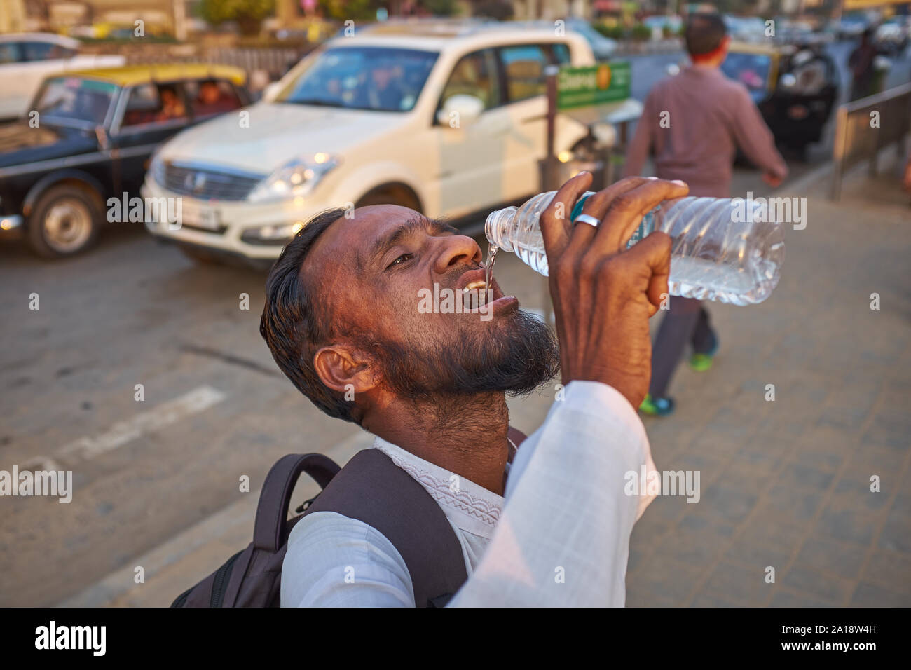 Un homme à Mumbai, Inde, des boissons de l'eau d'une bouteille en plastique, conformément à la coutume locale ou la notion de pureté, sans ses lèvres toucher la bouteille Banque D'Images