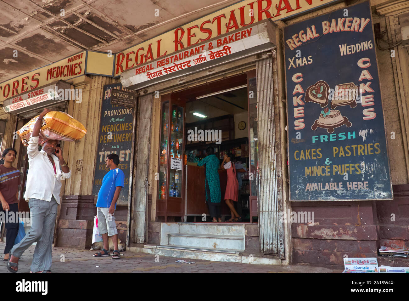 Les gens qui passent à l'extérieur de quaintly démodé à Regal Restaurant, un 'vintage' Irani eatery/boulangerie en zone Byculla, Mumbai, Inde Banque D'Images