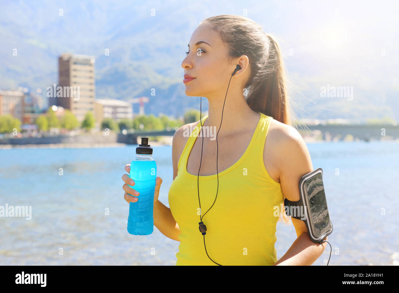 Athlète féminine de soif avec brassard pour téléphone intelligent au pouvoir boire et à la route à l'extérieur. Banque D'Images
