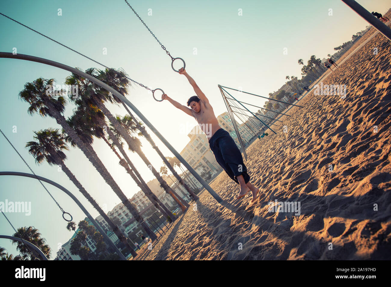 Un jeune homme sportif travaillant sur des anneaux de voyage sur Muscle Beach, Santa Monica, Californie Banque D'Images