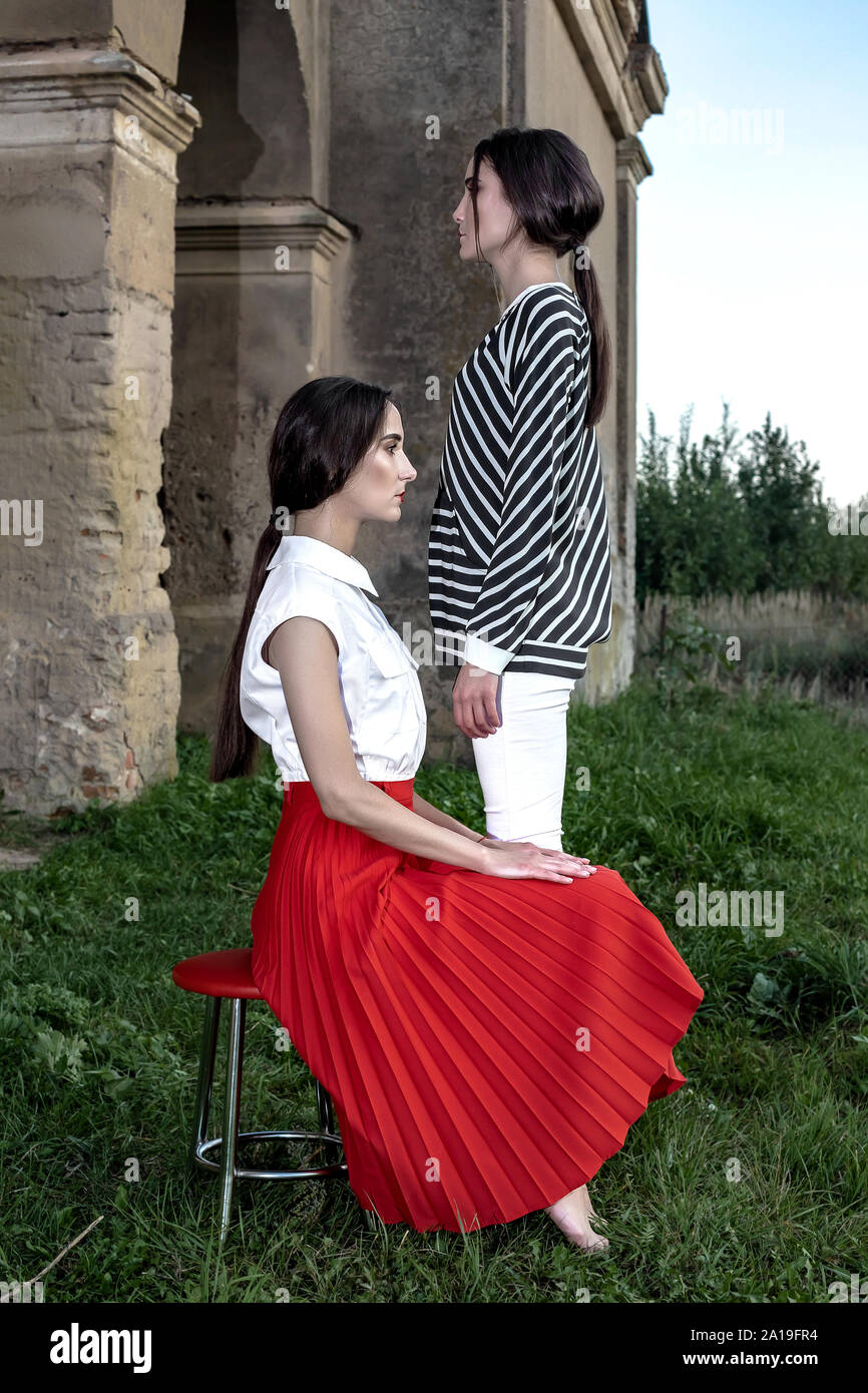 Piscine fashion portrait de deux jeunes et belles femmes portant des vêtements à la mode qui posent sur la rue dans le contexte d'un vieux abandonné buil Banque D'Images