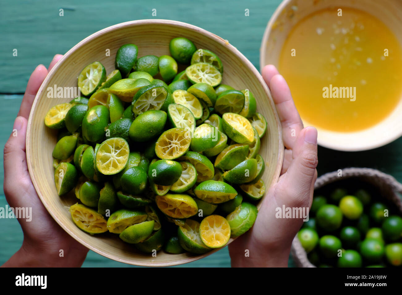 Vue supérieure de la main des gens en vert peel kumquat que évincés de fruits, cette sour fruit riche en vitamine C, en bonne santé et faire boire de detox Banque D'Images